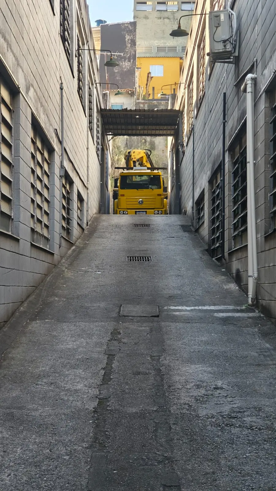 Munck acessando via estreita entre edificações