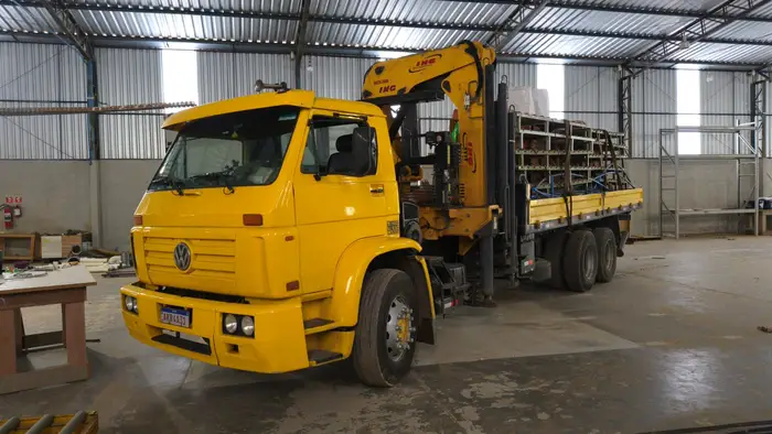 Carregamento de materiais em carroceria dentro de galpão
