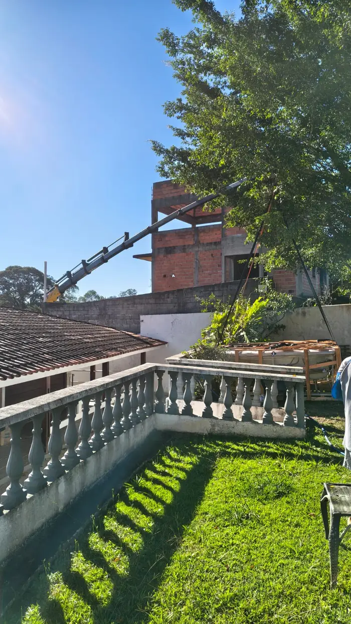 Lança do Munck alcançando obra residencial por trás de muro